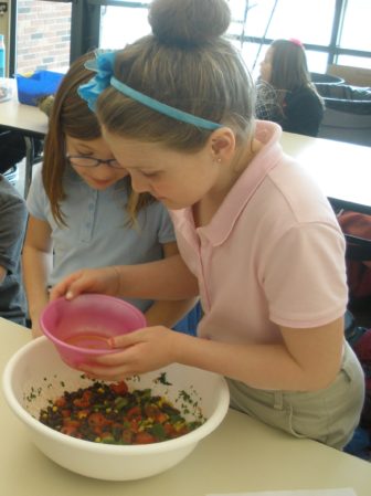 Two girls making salsa together in the classroom