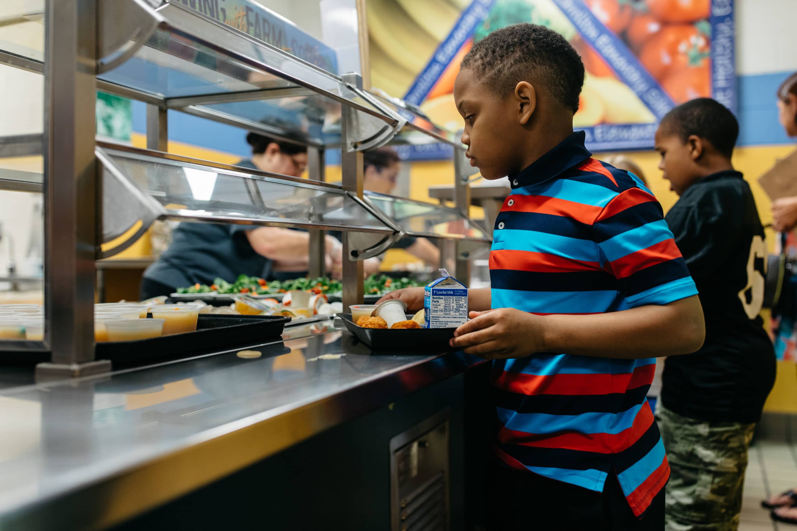 A child reaches for a side dish in the school cafeteria line.