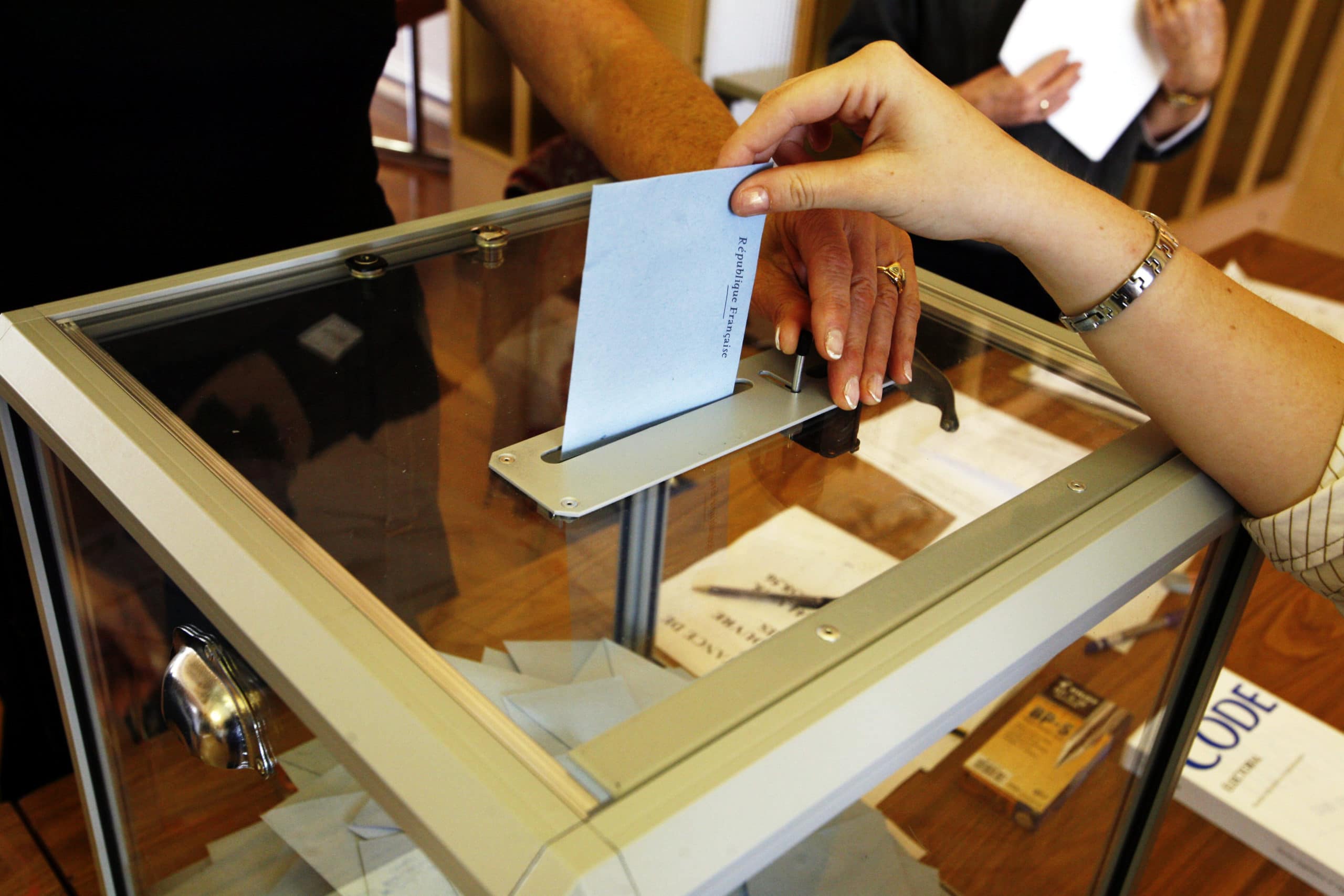 A hand places a ballot into a box. Local elections matter more than you may think!