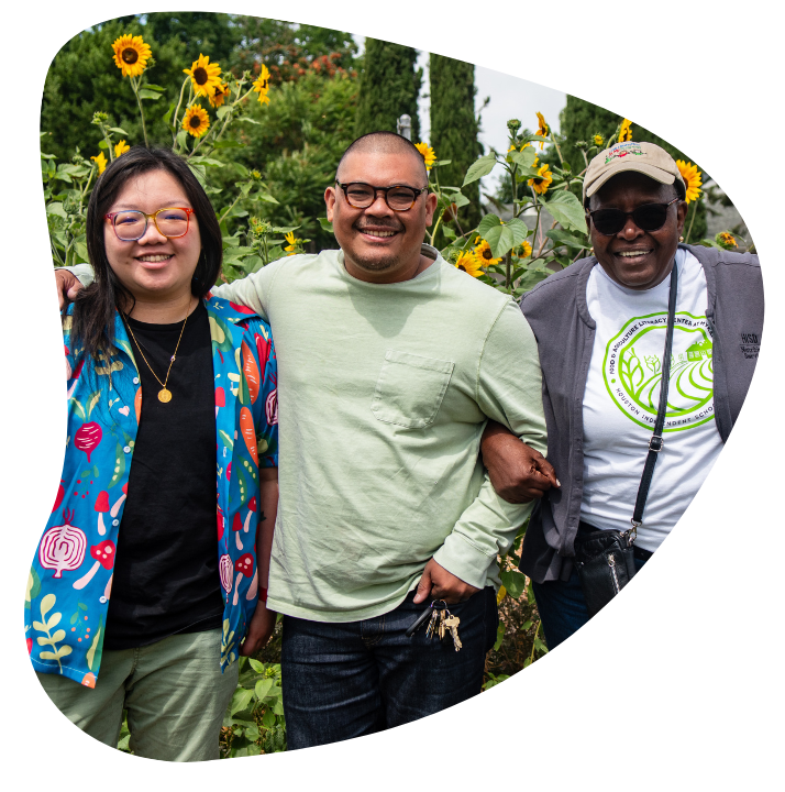 Three members of FOLCS standing in front of sunflowers, smiling