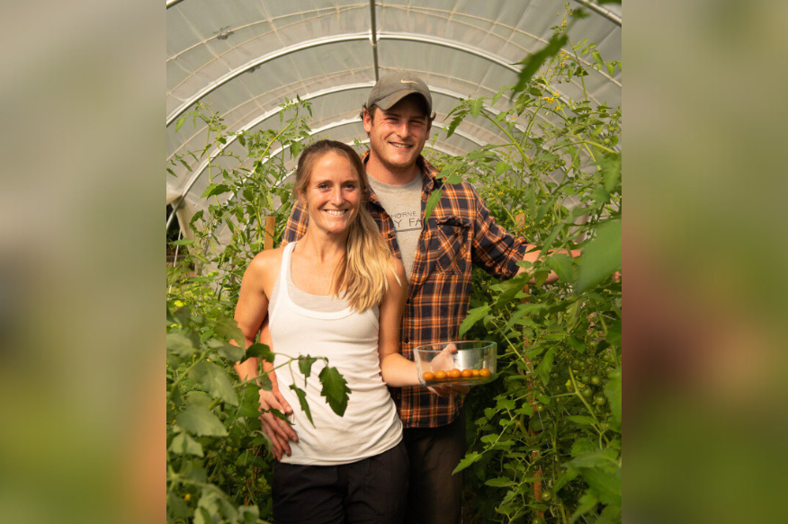 Alumni farmer Christopher Horne and his wife, Michaela, stand smiling and surrounded by plants.