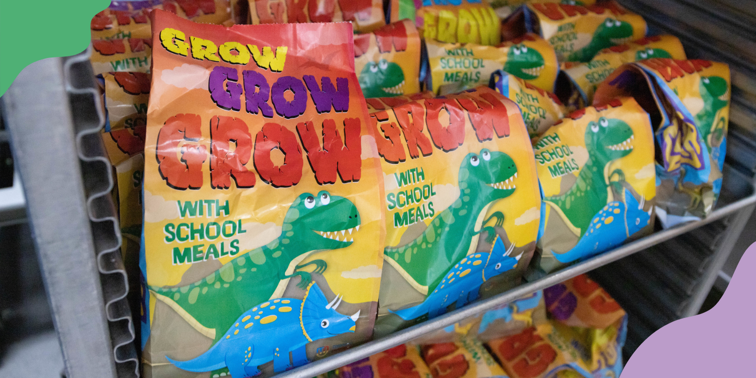 A line of colorful school lunch bags read "GROW GROW GROW with school meals" and feature images of cartoon dinosaurs. Policy changes that support summer meal access are good for all kids.