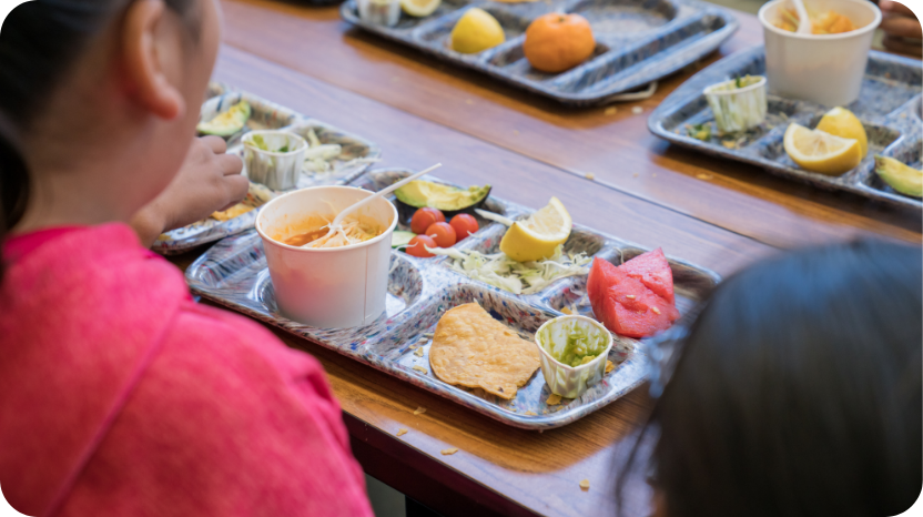 The back of a student sitting at a lunch table with a tray of food