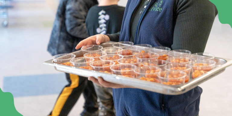 A person holding a tray of taste test samples at torso height. The sample cups are filled with colorfully seasoned chickpeas. Food service directors represent one sector of careers in food that help kids and schools.