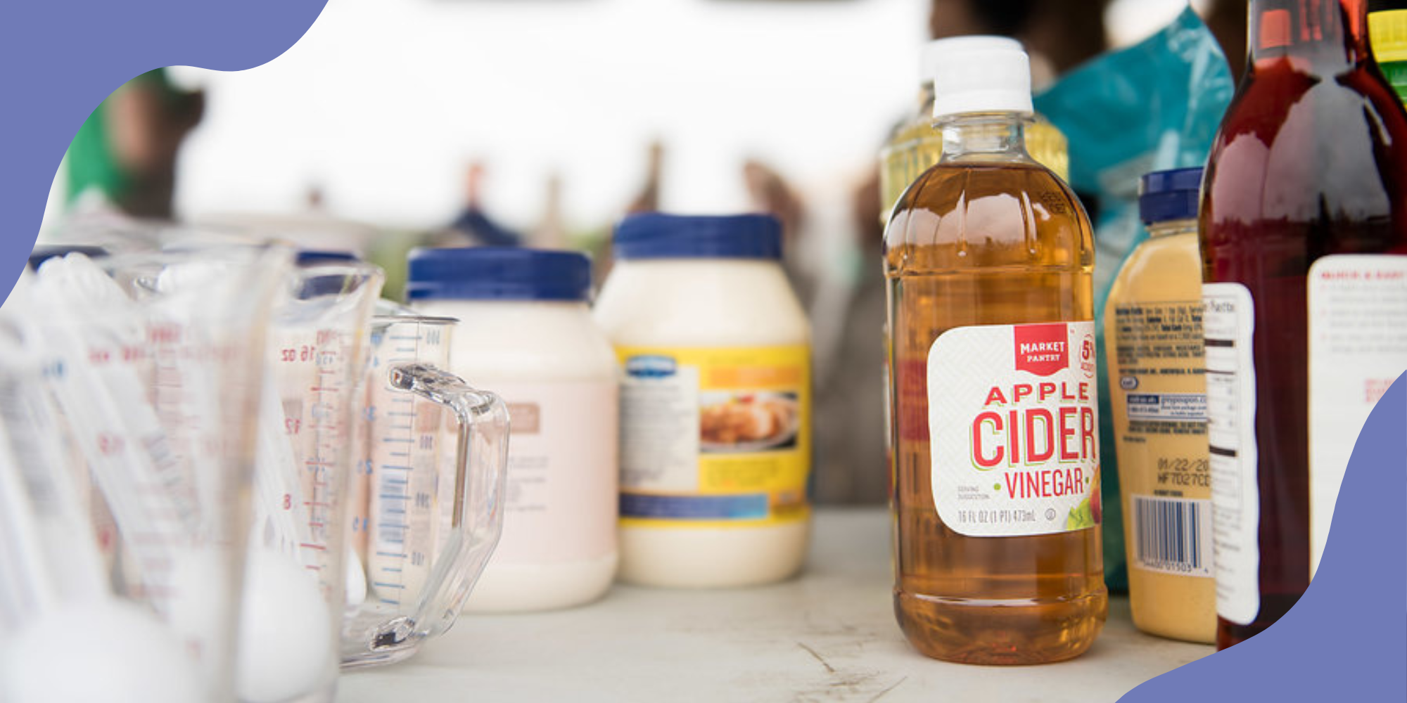 An array of condiments and sauces, some ultraprocessed and some not, standing on a white table in bright outdoor light.