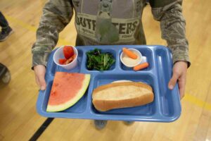 A student holding a blue lunch tray.