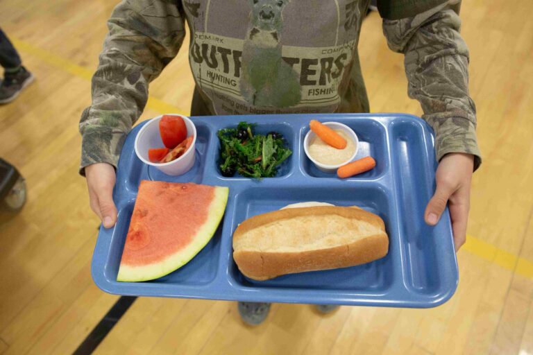 A student holding a blue lunch tray.